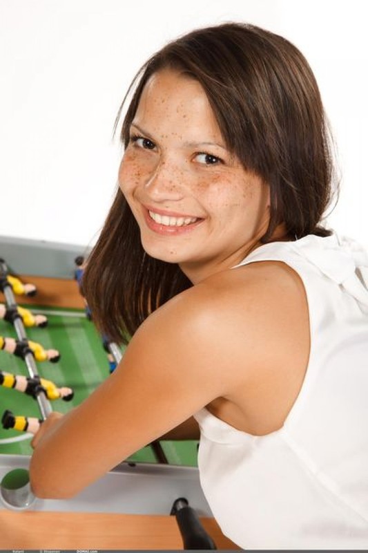 Девушка с веснушками извивается возле футбольного стола